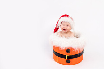 little baby girl sitting in Santa hat in basket on white isolated background, happy new year 2021, space for text