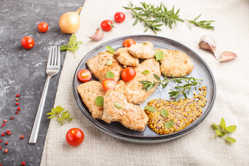 Fried pork chops with tomatoes and herbs on a gray ceramic plate on a black concrete background. side view.