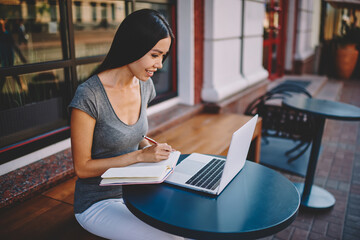 Positive brunette female freelancer satisfied with free schedule completing task online,skilled...