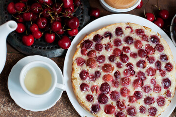 Tart with ripe sweet cherries and green tea on brown background. Homemade dessert with ripe sweet cherries. Top view