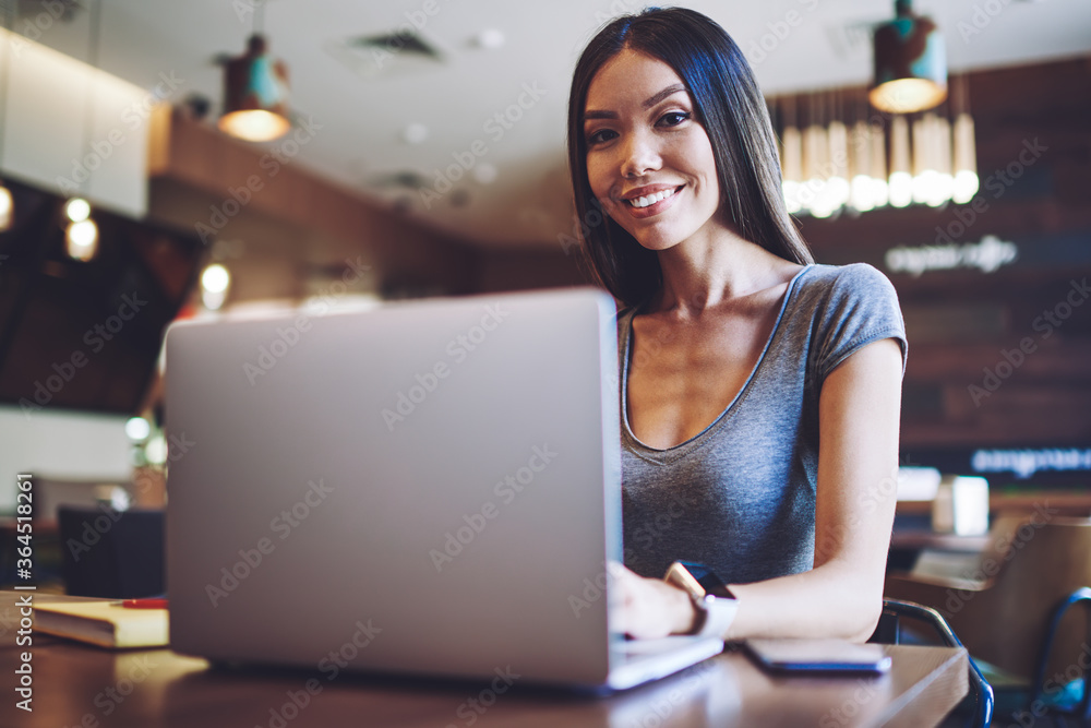 Poster portrait of happy female student resting in comfortable cafeteria with modern laptop computer for e 