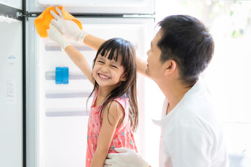 Asian daughter is helping father to clean the refrigerator with fully happiness moment, concept of kid executive function development by housework responsibility and happy time in family lifestyle.