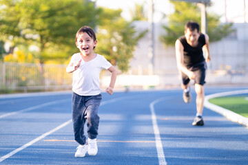 Asian little daughter is running in the stadium together with father, concept of outdoor activity, sport, exercise and competition learning for kid development.