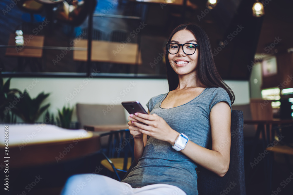 Poster portrait of cheerful hipster girl in new spectacles looking at camera while updating software setups