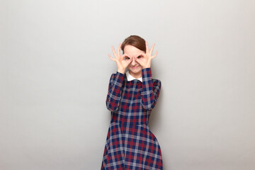 Portrait of happy girl showing okay gestures with fingers near eyes