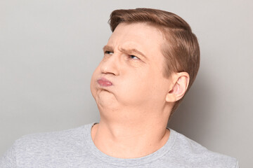 Portrait of funny goofy man puffing out his cheeks and pouting lips