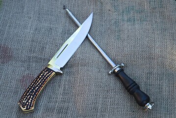 High angle view of a hunting knife and a knife sharpener on the table under the lights