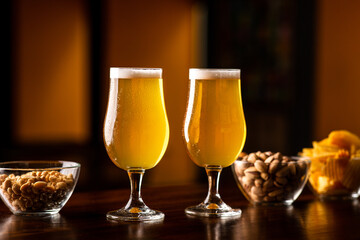 Crispy snacks for client. Two glasses of light beer and chips and nuts on bar