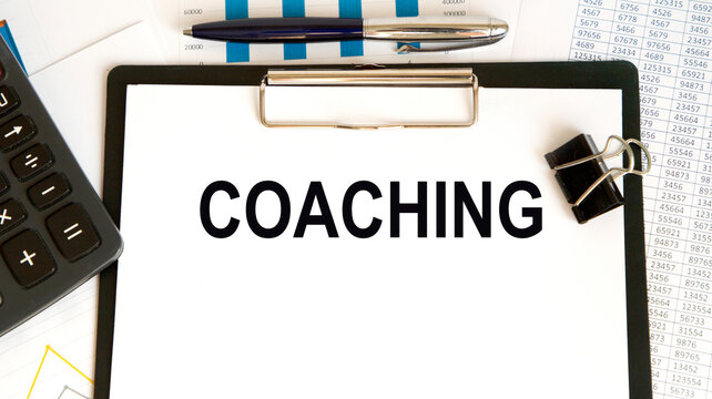 On a white notebook is an oversupia coaching, business concept, a number of highlighters, rkka, glasses, diagrams and graphs.