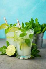 Two homemade lemonade or mojito cocktail with lime, mint and ice cubes in a glass on a light stone table. Fresh summer drink.