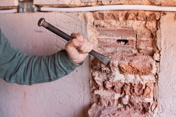Worker breaking the wall with hammer and chisel in a construction site