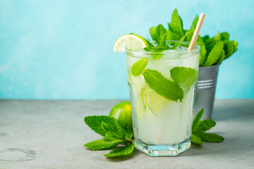 homemade lemonade or mojito cocktail with lime, mint and ice cubes in a glass on a wooden rustic table. Fresh summer drink. with copy space.