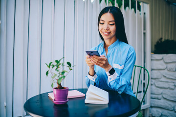 Charming happy asian brunette woman enjoying recreation during sending funny messages to friends via application on smartphone connected to 4G.Pretty smiling hipster girl watching videos in websites