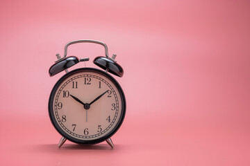 closeup of beautiful black alarm clock on pink background wit copy space.