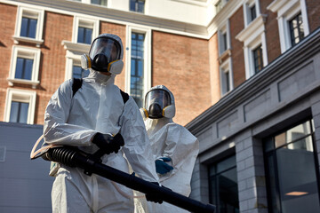 professional specialized fearless team in white protective suits and masks ready to work, clean...