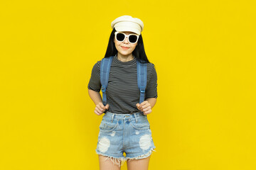 Traveler tourist beautiful young asian woman in casual clothes and sunglasses with Backpack isolated on yellow background.Summer holidays, vacation and travel concept