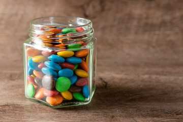 lentejas de chocolate en un frasco sobre un fondo de madera con foco selectivo