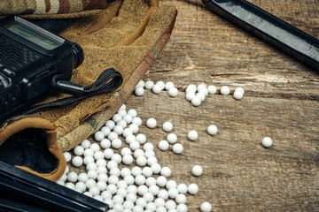 Close up of airsoft gun magazine and airsoft balls on wooden background