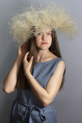 Portrait of young brunette girl in fluffy wreath of feather grass, florist girl on gray background