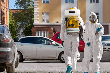 professional cleaning and disinfection of the territory in the city due to the emergence of Covid-19 virus. specialized friendly team in protective suits clean surface with equipment