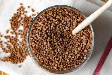 Bowl of raw uncooked buckwheat on wooden table