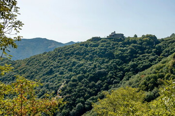 Panorama with peaks overgrown with old green forest and a view of the Glozhene Monastery in the distance in the Balkan Mountains near the town Teteven , Bulgaria 