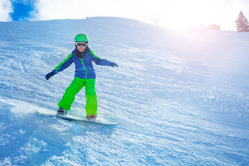 Fast action photo of a boy going downhill on snowboard view from side balancing with hands and snow...