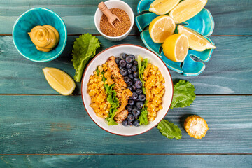 Grilled chicken breast with fresh blueberries, arugula and corn close-up on a plate on a table. top view