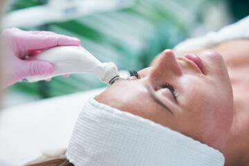 Adult woman in beauty salon undergoing face hydrogen purification