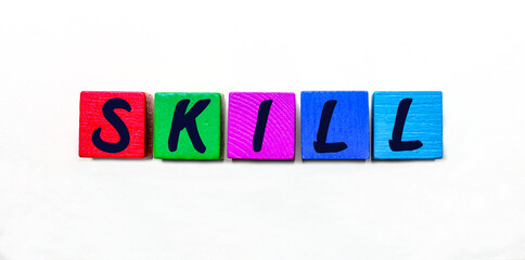 The word SKILL is written on various wooden cubes on a white table. Educational concept