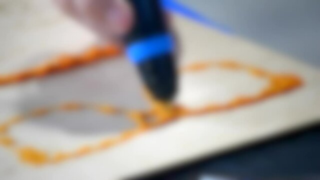 Blurred background. 3d drawing pen. A man draws a figure in the form of glasses