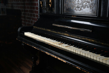 Fototapeta na wymiar old black piano with copper candlesticks against a brick wall