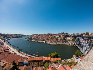 Obraz premium The Dom Luis I Bridge over the Douro River and the colorful houses of Porto Ribeira, traditional facades, old multi-colored houses with red roof tiles on the embankment in the city of Porto, Portugal.