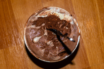 A close-up high angle view of a small bucket of melting chocolate ice cream with a spoon 