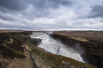 Famous Gulfoss waterfall in the Golden Circle in South Iceland. Tourists walk on a path to the viewpoint. Wide landscape view
