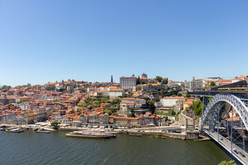 The Dom Luis I Bridge over the Douro River and the colorful houses of Porto Ribeira, traditional facades, old multi-colored houses with red roof tiles on the embankment in the city of Porto, Portugal.