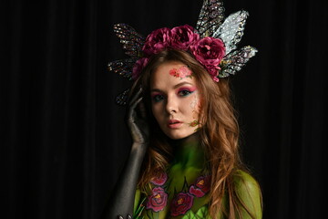 beautiful girl painted with green paint and flowers on her face and burgundy peonies in her body posing in different poses