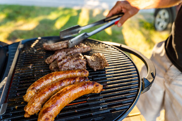 Man cooking chorizo and steak on a portable bbq