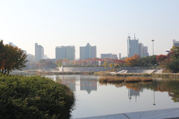 Fototapeta na wymiar 서울 올림픽공원 호수 너머로 보이는 평화의 광장과 호수에 비치는 건물들