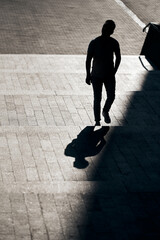 The silhouette of guy with glasses, who rises up a concrete staircase to the top, creating an interesting reflection from his shadow. Art and street photography. Cool frame composition.