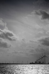 Windmills off the coast of Urk in the IJsselmeer in the evening with cloudy sky, seen from Lemmer, The Netherlands. Vertical image