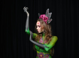 beautiful girl painted with green paint and flowers on her face and burgundy peonies in her body posing in different poses