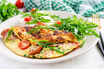 Omelette with tomatoes, cheese and green herbs on plate.  Frittata - italian omelet.