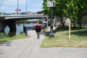 Geneva, Illinois, USA. July 1, 2020. A man enjoys cycling on the trail along the Fox River.