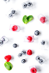 fresh berries with mint in ice cubes on white background top view
