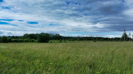 Landscape. Field, trees, sky with clouds, electrical communication.