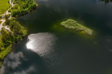 Drone view from above of small grass island in the forest lake. Summer landscape.