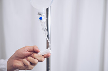 Close up saline IV drip Infusion doctor adjusted volume rate of intravenous fluid bottle with IV...