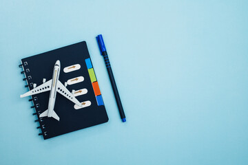 White airplane model with a checklist diary on blue background for travel planning concept