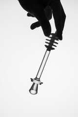 Silhouette of a male hand holding a glass spoon for honey. Black and white photo. Copy space. Studio photo.